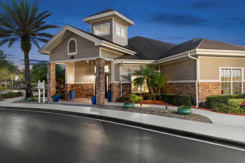 Community leasing center exterior in front of the road with palm tree and other landscaping on the sides.