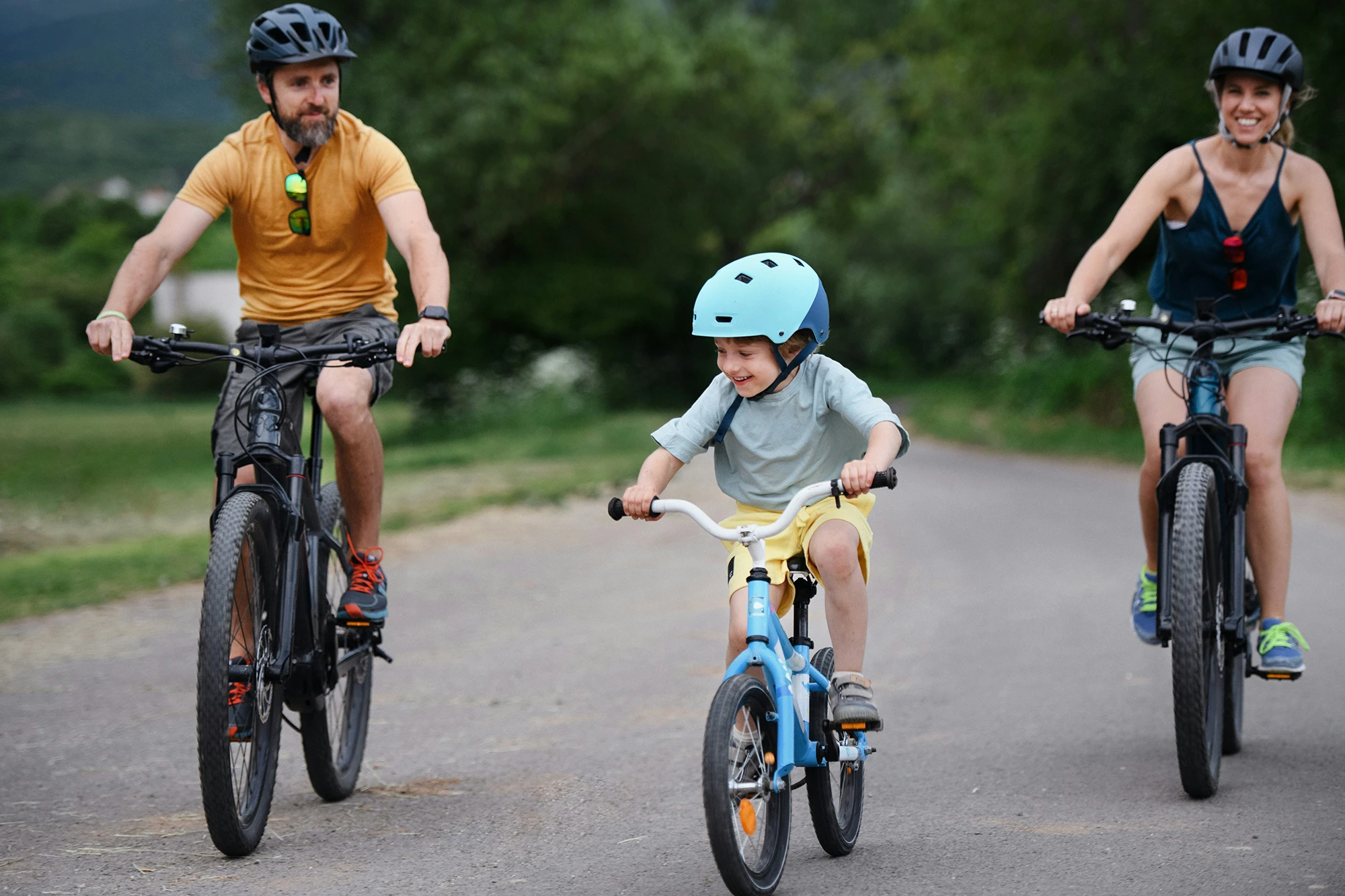 Man, woman and child biking on a trail with helmets.